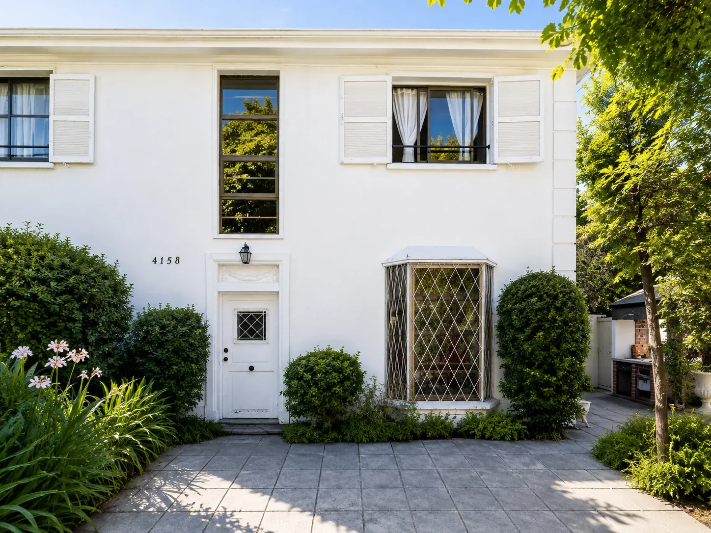 Fachada de una casa blanca con jardín.